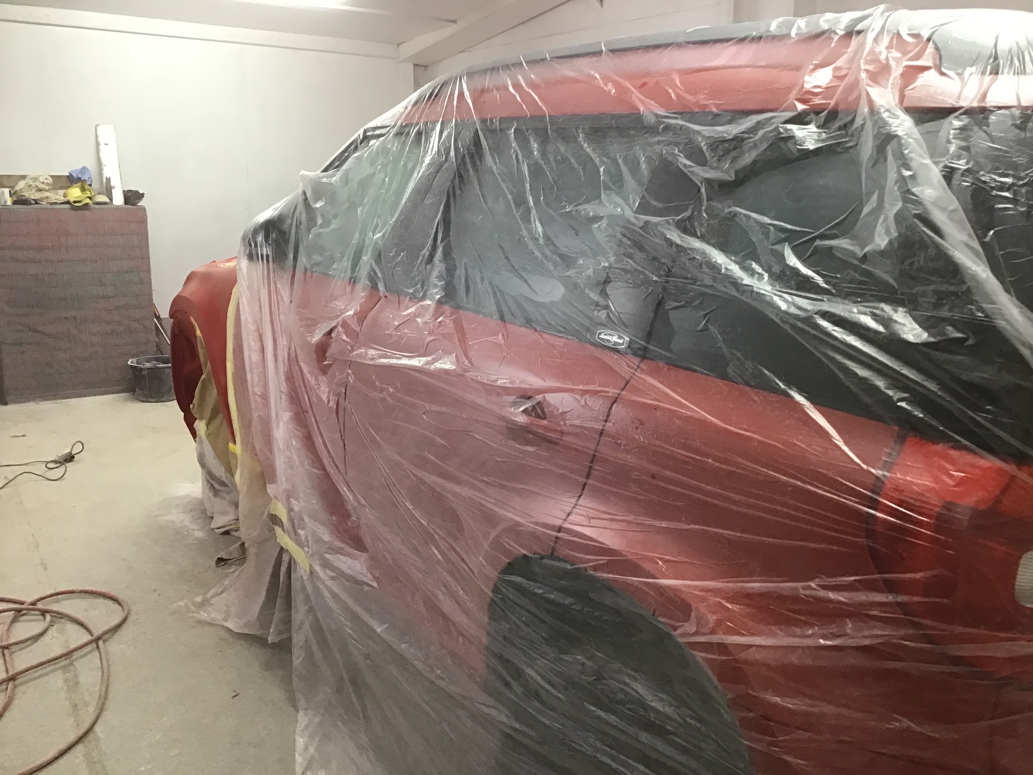A red car carefully masked for paintwork inside the Woods Forge Garage workshop